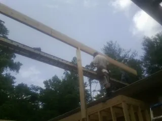 Carpenter setting a ridge beam over a new addition frame — Ice Dam Removal by Roofing Brothers in Canehill