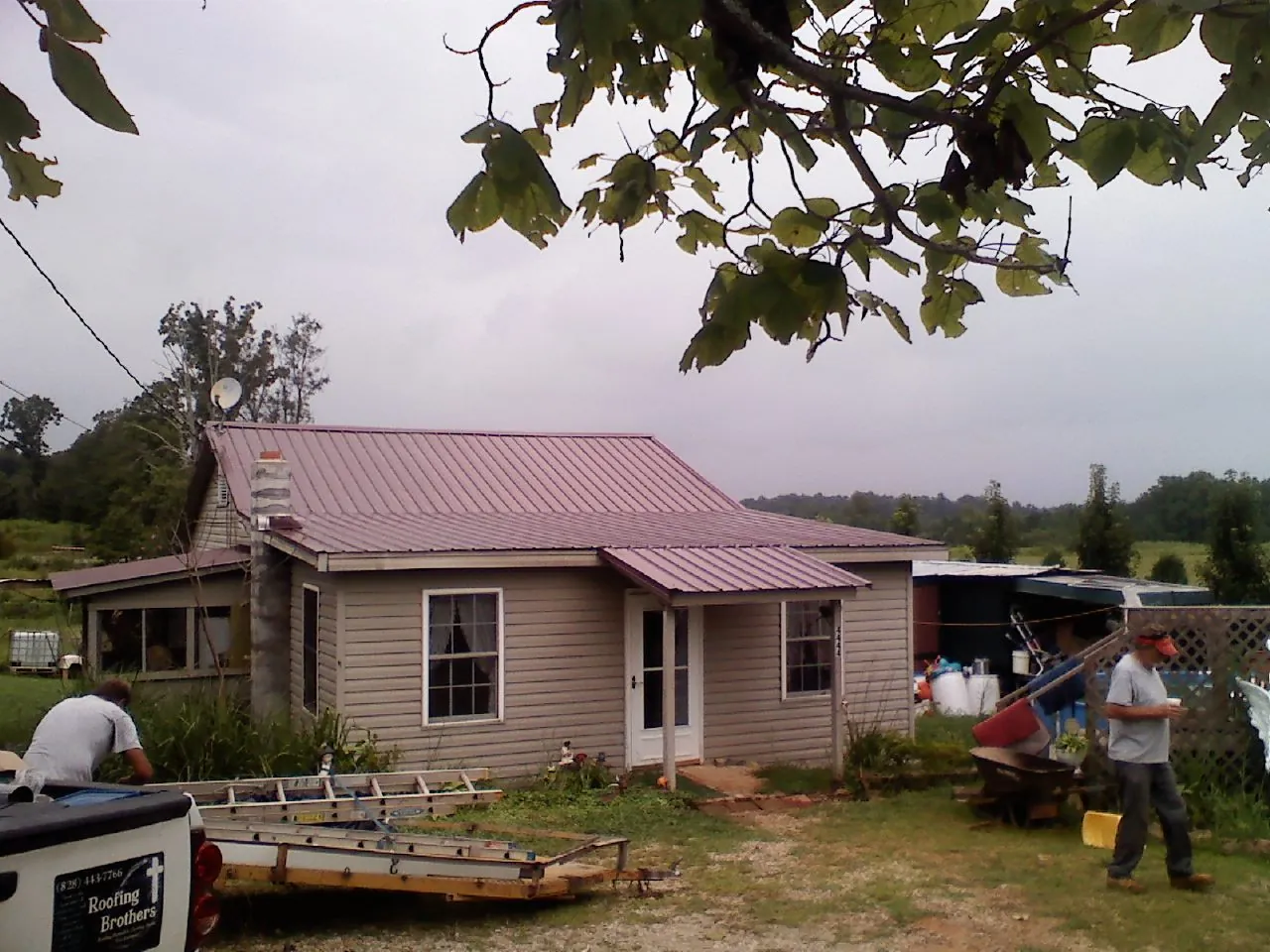 Crew finishing a mauve metal roof on a small farmhouse in Canehill