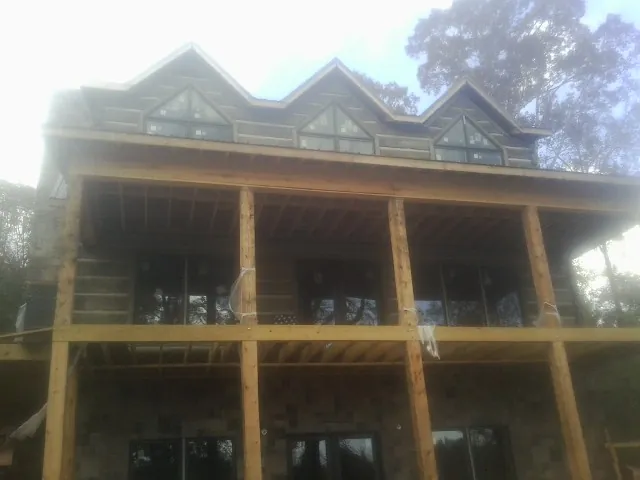 Dormers and porch framing on a large log home under construction — Roof Coating work by our crew in Canehill