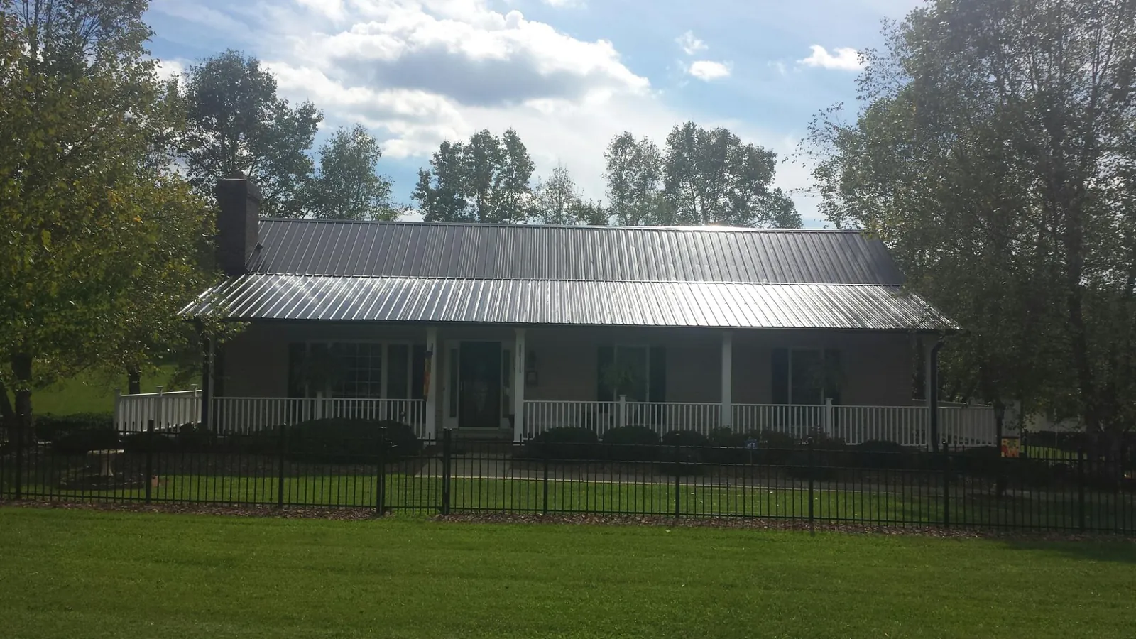 Gray metal roof on a brick ranch with a full width front porch — Gutter Guard Installation work by our crew in Canehill