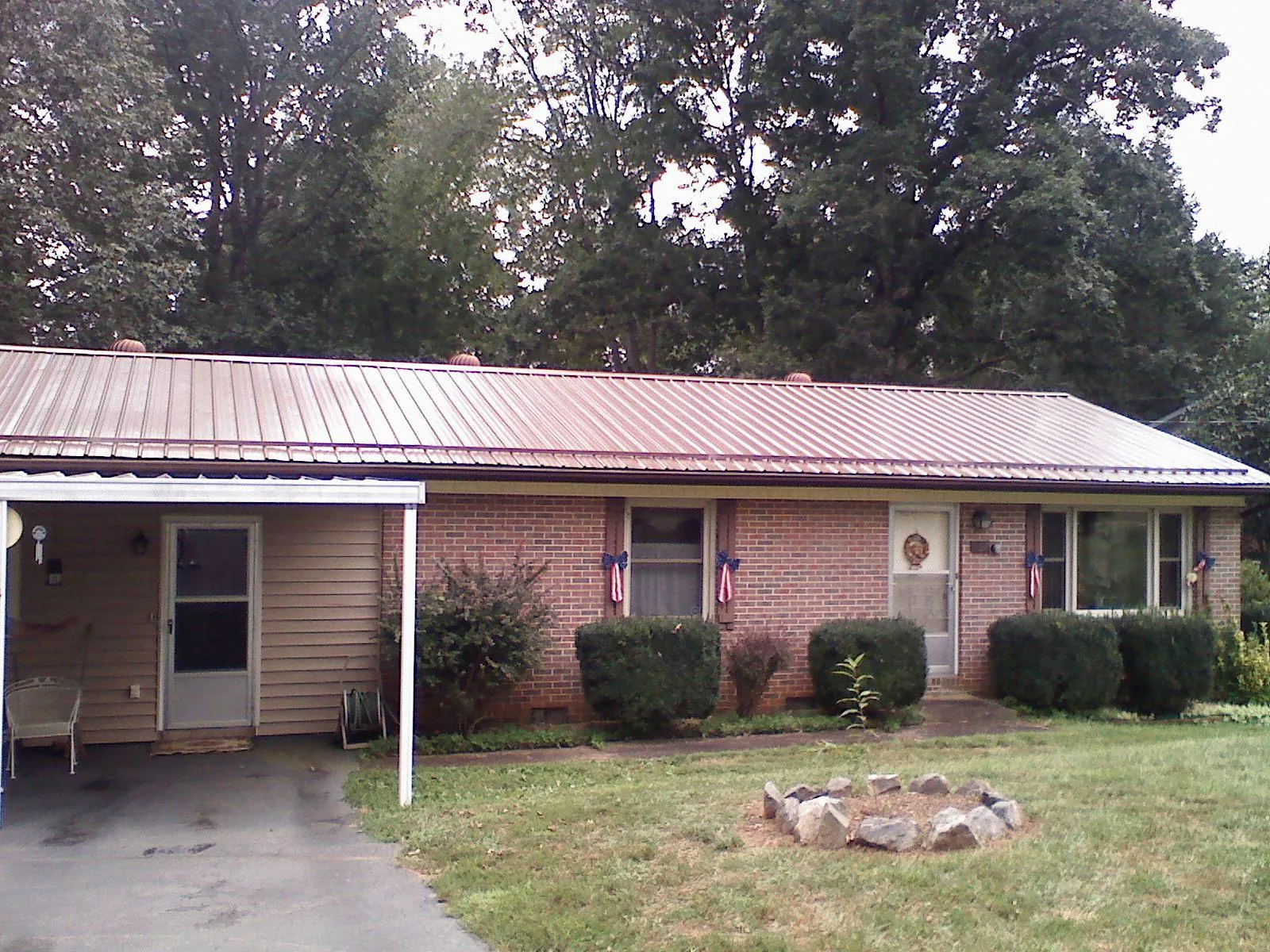 Bronze metal roof and carport on a brick ranch home — Roof Repair work by our crew in Canehill