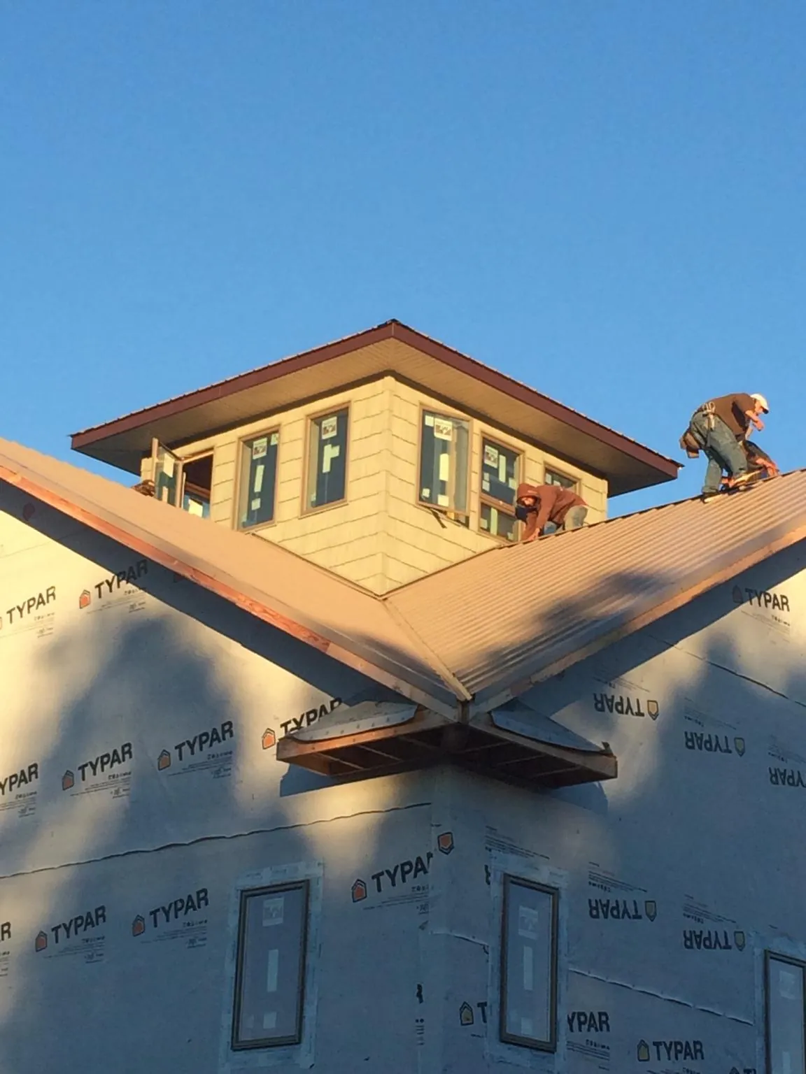 Roofers working around a rooftop cupola on a new metal roof at sunset — Roof Waterproofing in Canehill by Roofing Brothers
